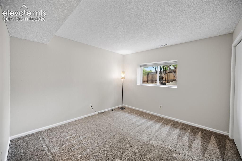 Image 27 of 37: Carpeted room featuring a single window, white trim, and a white bi-fold cl