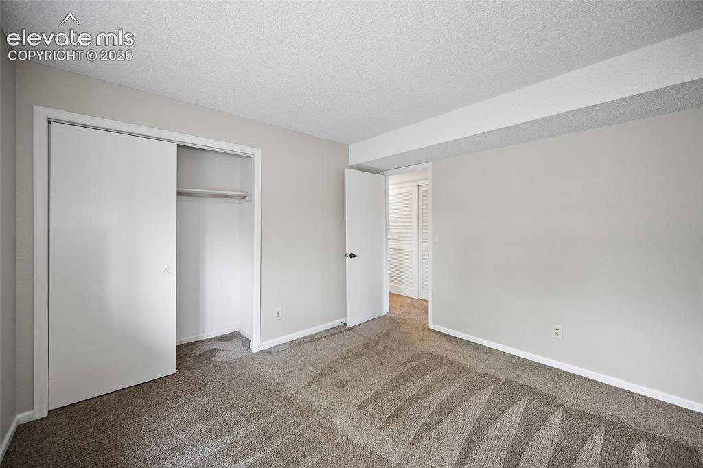 Image 28 of 37: Carpeted room featuring a double-door closet with internal shelving, neutra