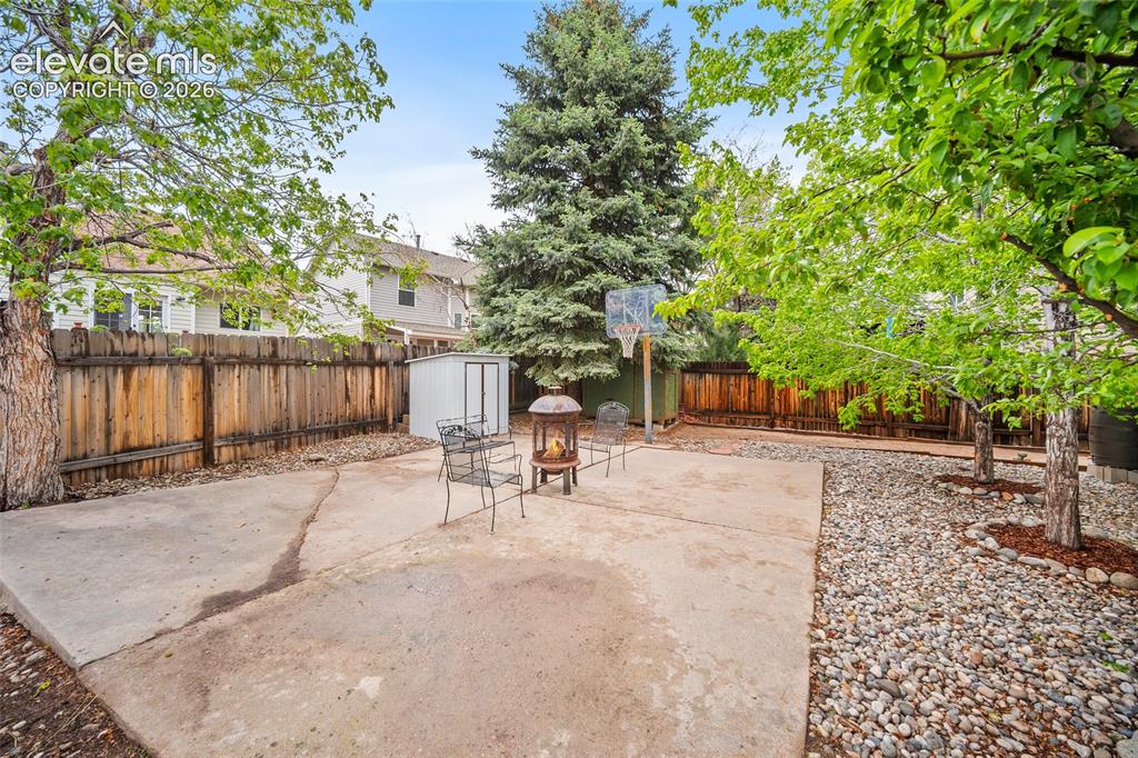 Image 31 of 37: Backyard featuring an expansive concrete patio, a privacy fence, mature tre