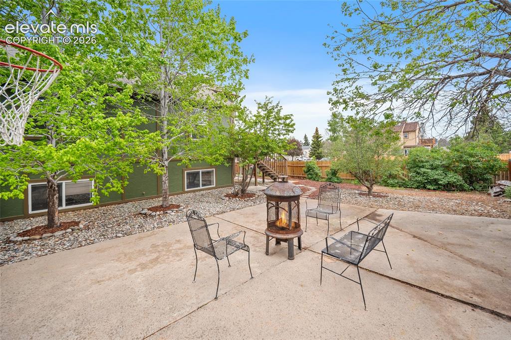 Image 32 of 37: Expansive concrete patio area featuring a central fire pit