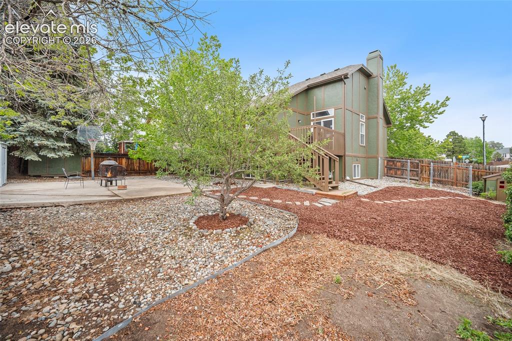 Image 33 of 37: Expansive rear yard featuring a concrete patio and a sloped terrain