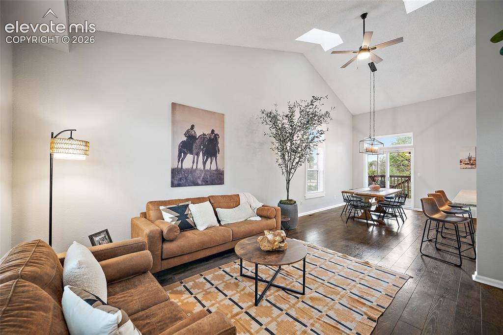 Image 4 of 37: Vaulted ceiling living area featuring dark wood-finish flooring and skyligh