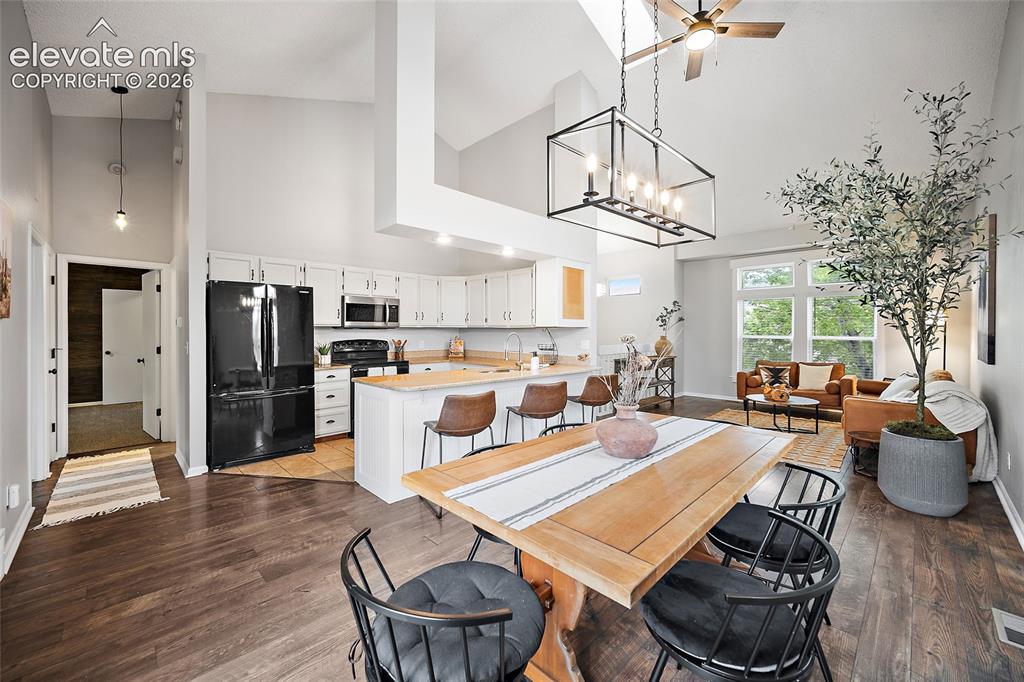 Image 5 of 37: Open-concept living space featuring vaulted ceilings, wood-finish flooring,