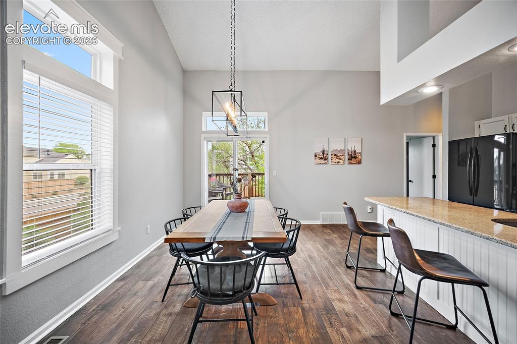 Image 6 of 37: Vaulted ceilings elevate this dining area, featuring wood-finish flooring a