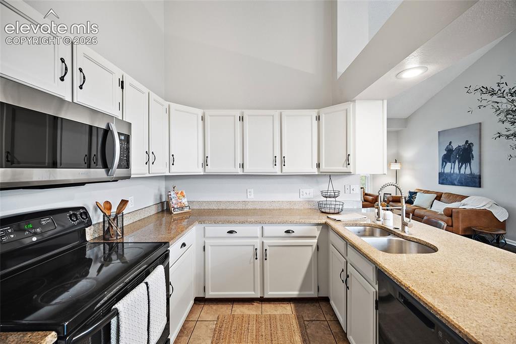 Image 7 of 37: Kitchen featuring white cabinetry, stone-finish countertops, and an undermo