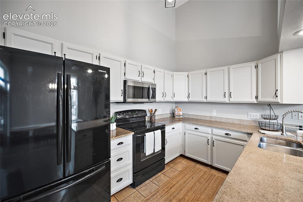Image 9 of 37: Kitchen featuring white cabinetry, light-toned countertops, a stainless ste