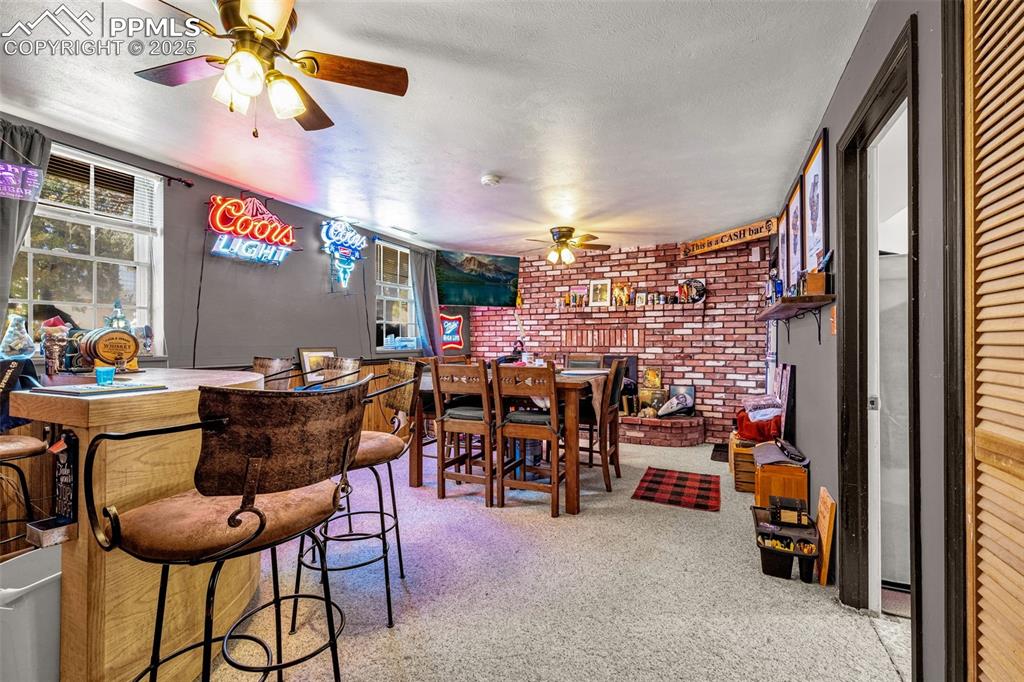 Image 14 of 25: Family Room with Fire place and ceiling fan, carpet flooring, brick wall, a