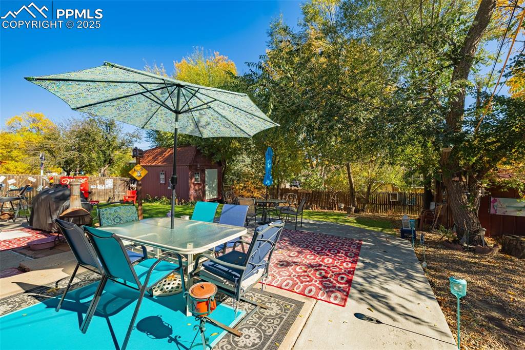 Image 16 of 25: Fenced backyard with outdoor dining space, an outbuilding, a patio area, an