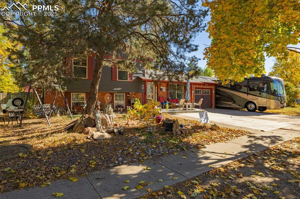 Image 2 of 25: View of front of home with driveway, a garage, and brick siding