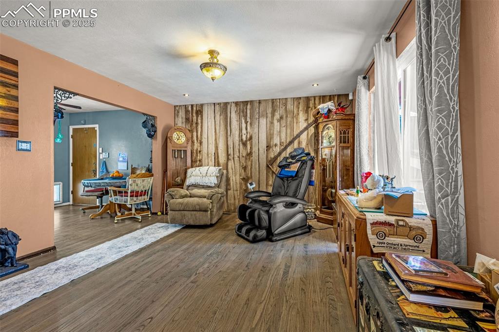 Image 3 of 25: Sitting room featuring wooden walls and wood finished floors