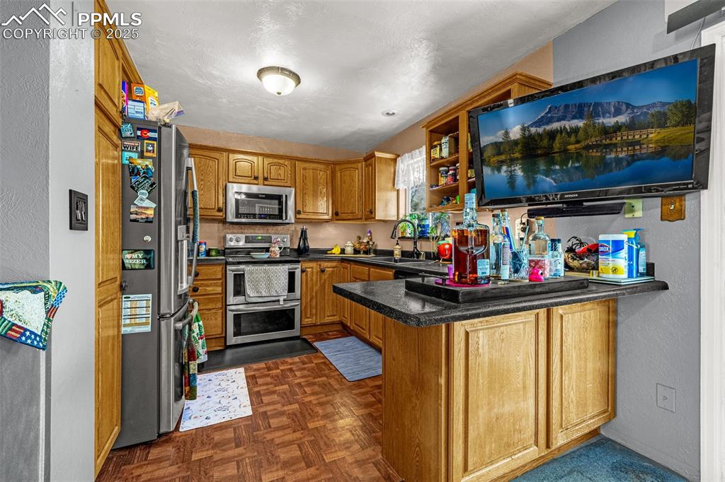 Image 5 of 25: Kitchen with a textured wall, a peninsula, appliances with stainless steel