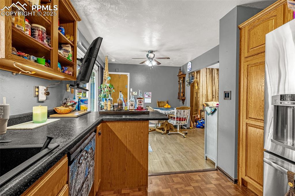 Image 6 of 25: Kitchen featuring dark countertops, stainless steel fridge with ice dispens
