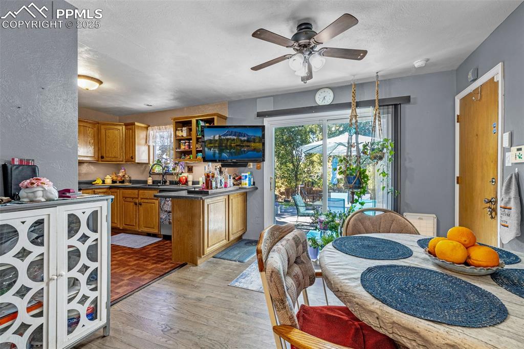 Image 7 of 25: Kitchen featuring brown cabinets, light wood-style floors, dark countertops