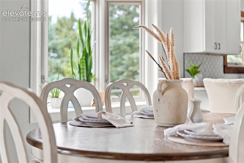 Image 13 of 49: Wood-finish dining table with light-toned chairs, abundant natural light, a