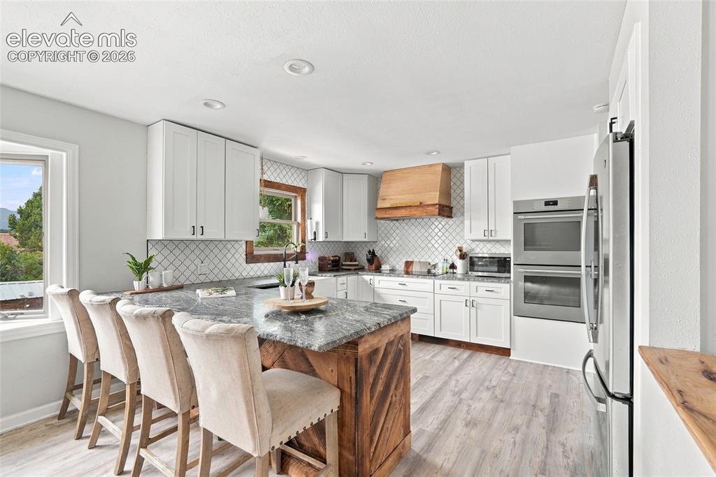 Image 14 of 49: White cabinetry with contemporary hardware, stainless steel double wall ove