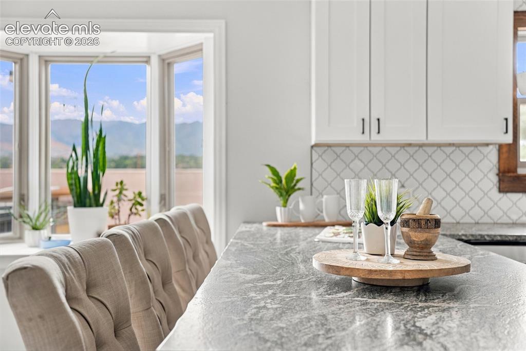 Image 17 of 49: White shaker cabinetry with matte black hardware, gray patterned backsplash