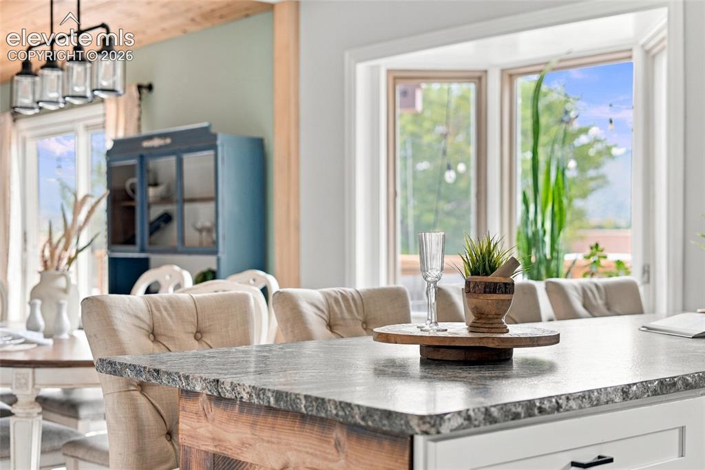 Image 2 of 49: Kitchen island featuring a natural stone countertop, wood-finish base, and 