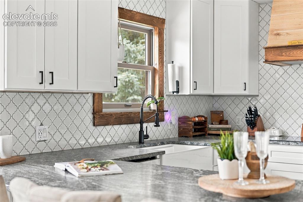 Image 20 of 49: White shaker-style cabinetry with black hardware, Arabesque tile backsplash