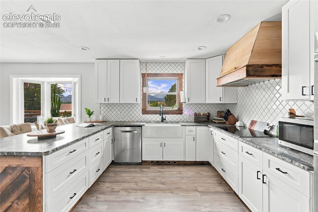 Image 21 of 49: White shaker cabinetry with black hardware, wood-finish flooring, stone cou