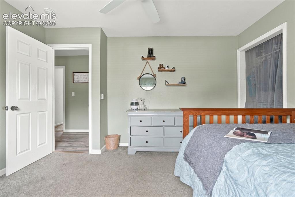 Image 23 of 49: Wall-to-wall carpeting, paneled interior door, and a ceiling fan