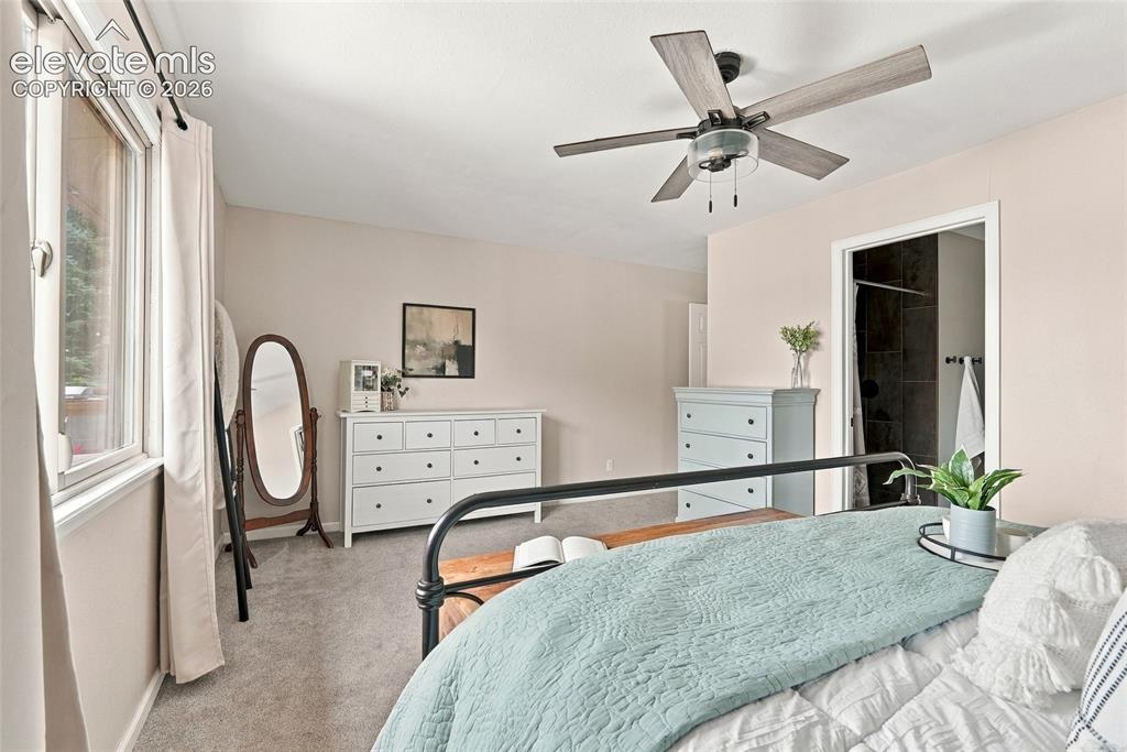 Image 28 of 49: Vaulted ceiling, ceiling fan with light fixture, window with trim, carpeted