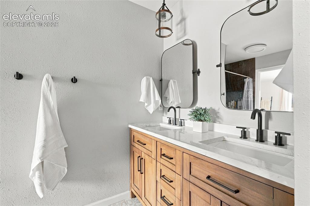 Image 29 of 49: Dual vanity with wood-finish cabinetry, integrated rectangular sinks, and m