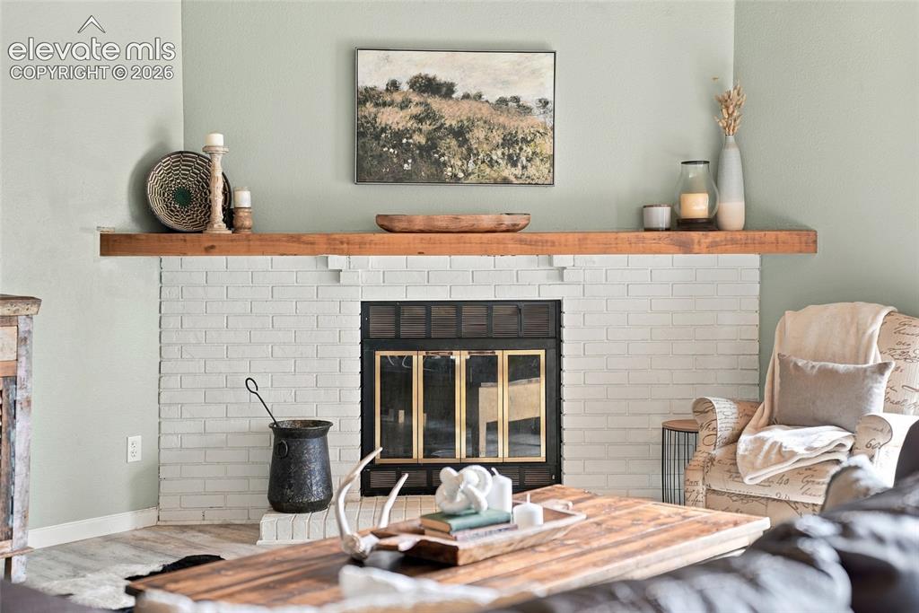 Image 3 of 49: White-painted brick fireplace with a wood mantle and a black firebox