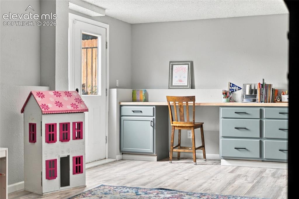 Image 30 of 49: Built-in desk with a wood-finish countertop, light blue cabinetry, and blac
