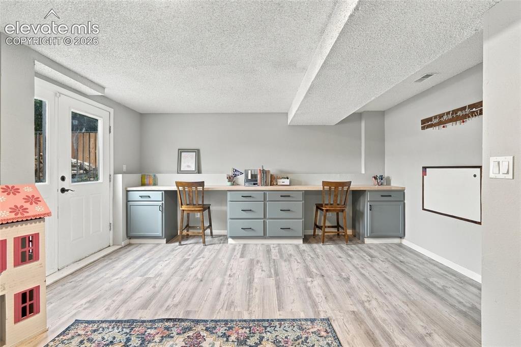 Image 31 of 49: Wood-finish flooring throughout, featuring a built-in desk with lower cabin