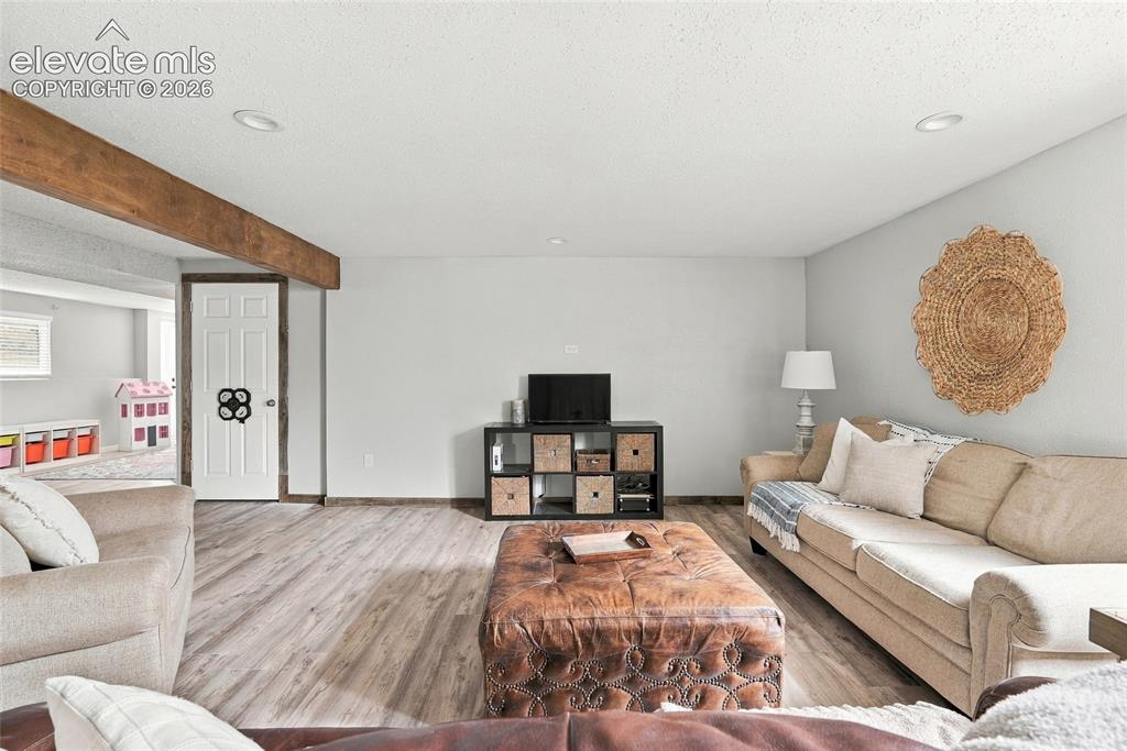 Image 34 of 49: Wood-finish flooring, recessed lighting, exposed beam, and white interior d