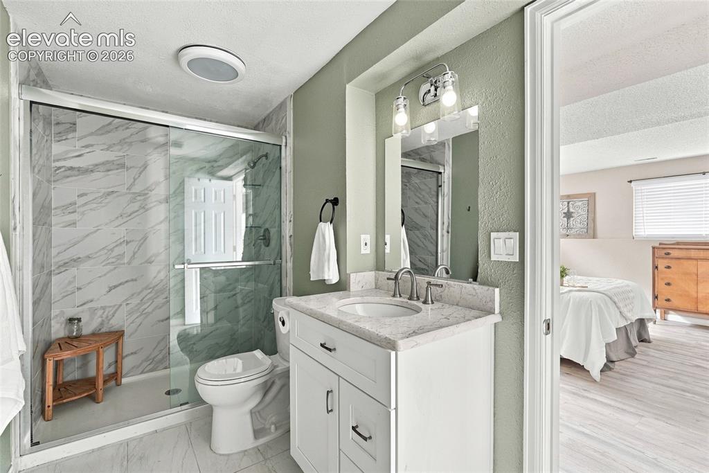 Image 42 of 49: Bathroom featuring a glass-enclosed shower with tiled walls, a vanity with