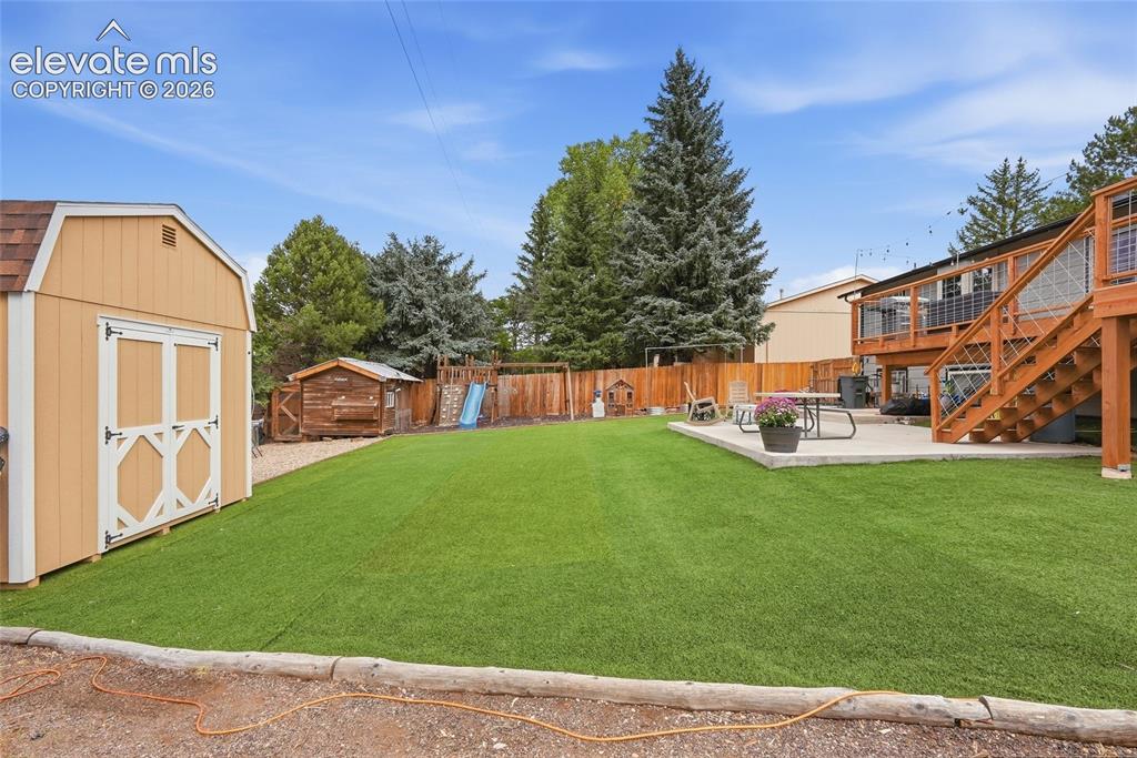 Image 46 of 49: Expansive artificial turf lawn, large concrete patio, multi-level wood deck