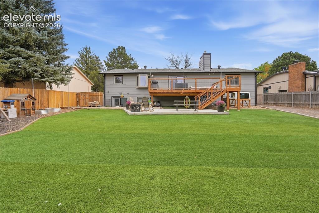 Image 47 of 49: Expansive artificial turf lawn with a multi-level wood deck featuring wood