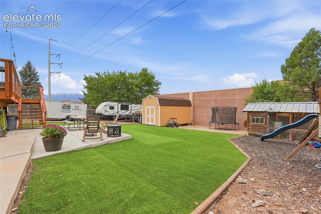 Image 49 of 49: Expansive backyard featuring a manicured artificial turf lawn, concrete pat