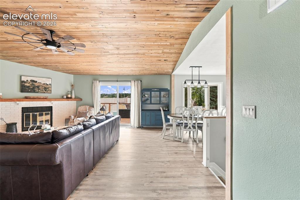 Image 6 of 49: Vaulted wood-finish ceiling with a ceiling fan, white brick fireplace, wood