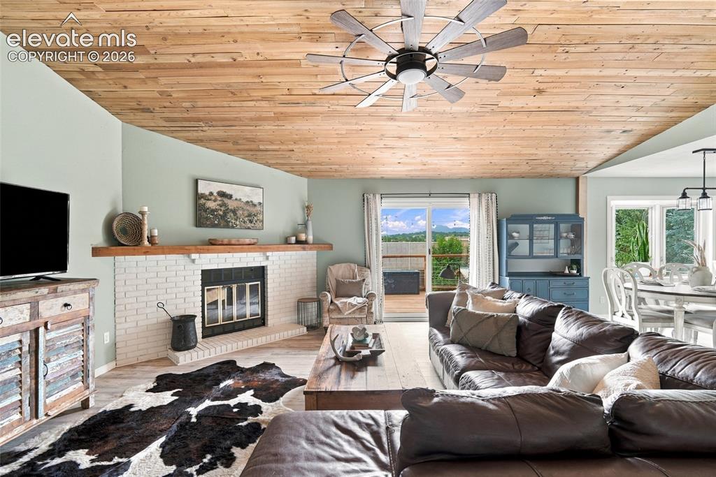 Image 8 of 49: Vaulted wood-finish ceiling, brick fireplace with wood mantel, and sliding