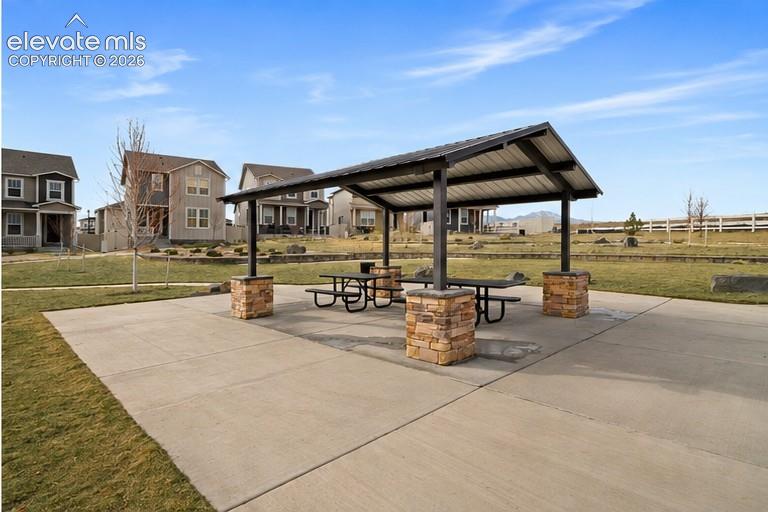 Image 23 of 45: Outdoor pavilion with a metal roof and stone-clad columns on a concrete pad