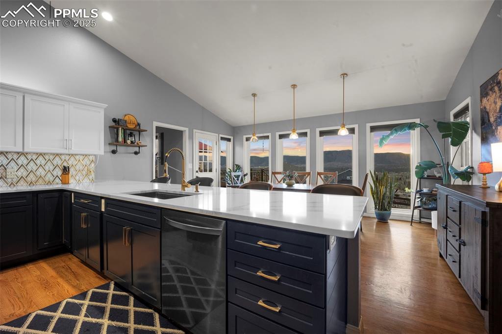 Image 13 of 50: Kitchen with stainless steel dishwasher, white cabinets, a sink, a peninsul
