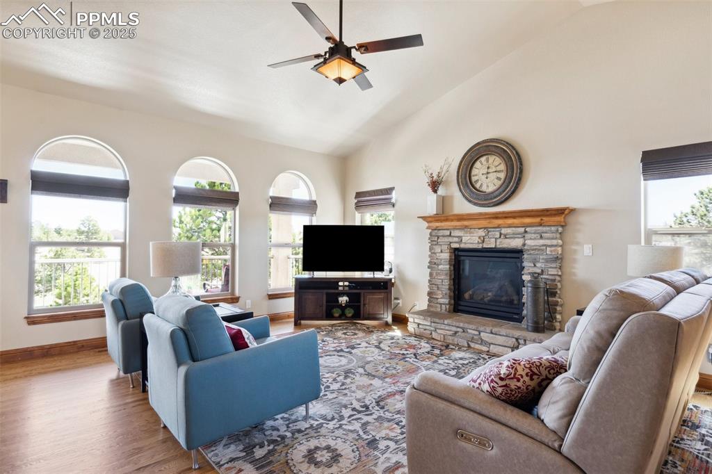 Image 11 of 46: Living area with plenty of natural light, a stone fireplace, a ceiling fan,