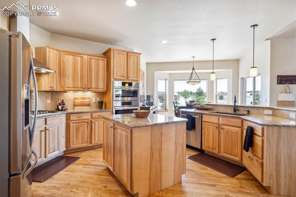 Image 12 of 46: Kitchen with a center island, range hood, appliances with stainless steel f