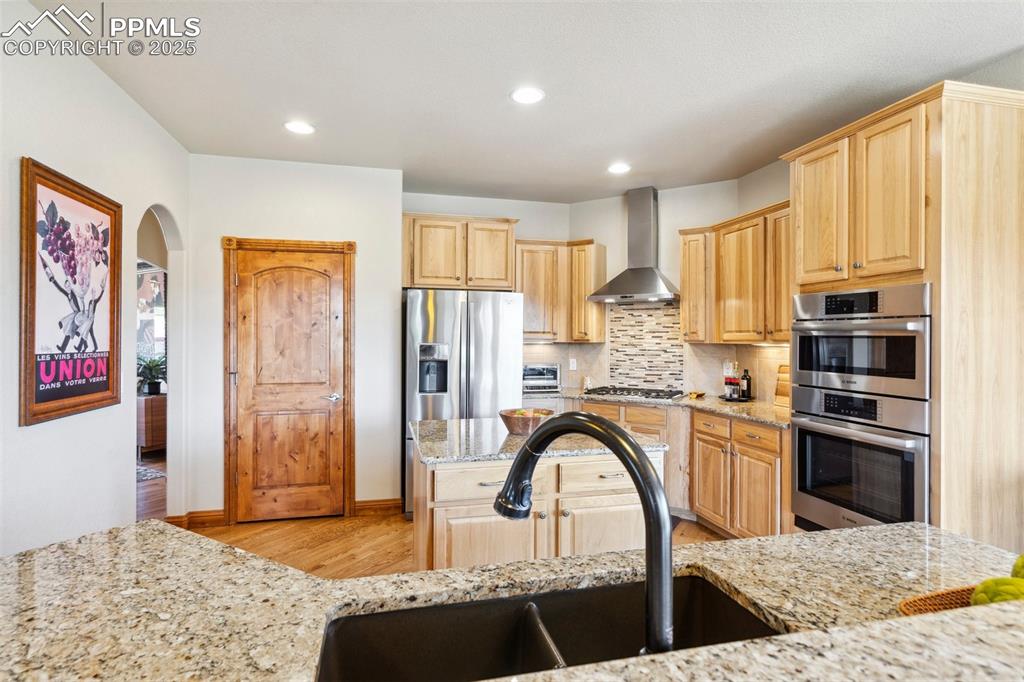 Image 13 of 46: Kitchen featuring range hood, light wood-style floors, appliances with sta