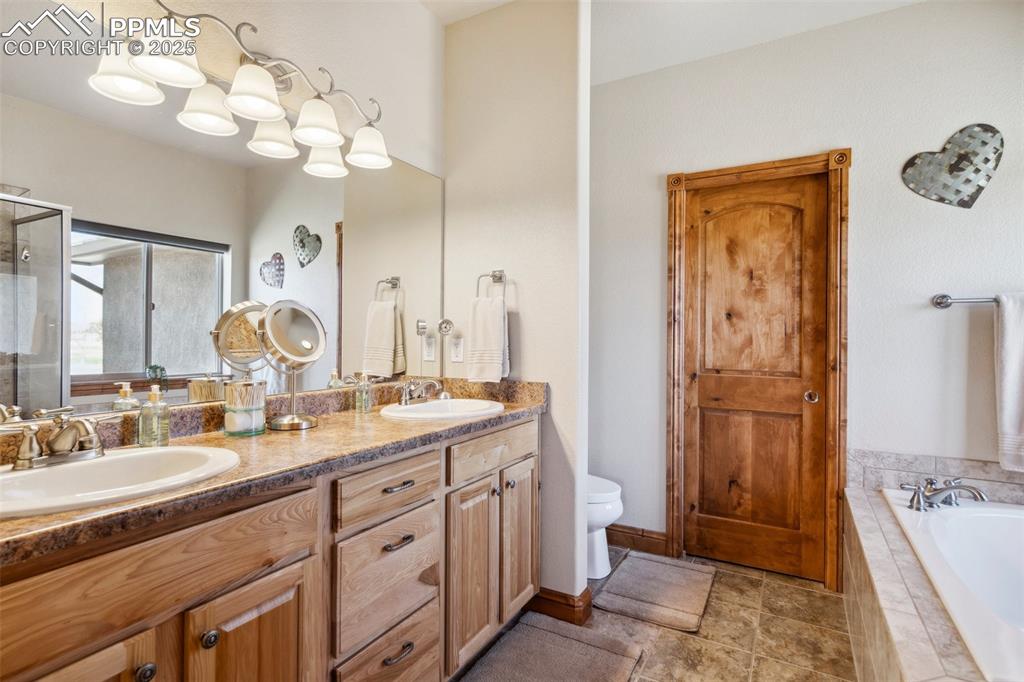 Image 20 of 46: Bathroom featuring toilet, a bath, double vanity, and a sink