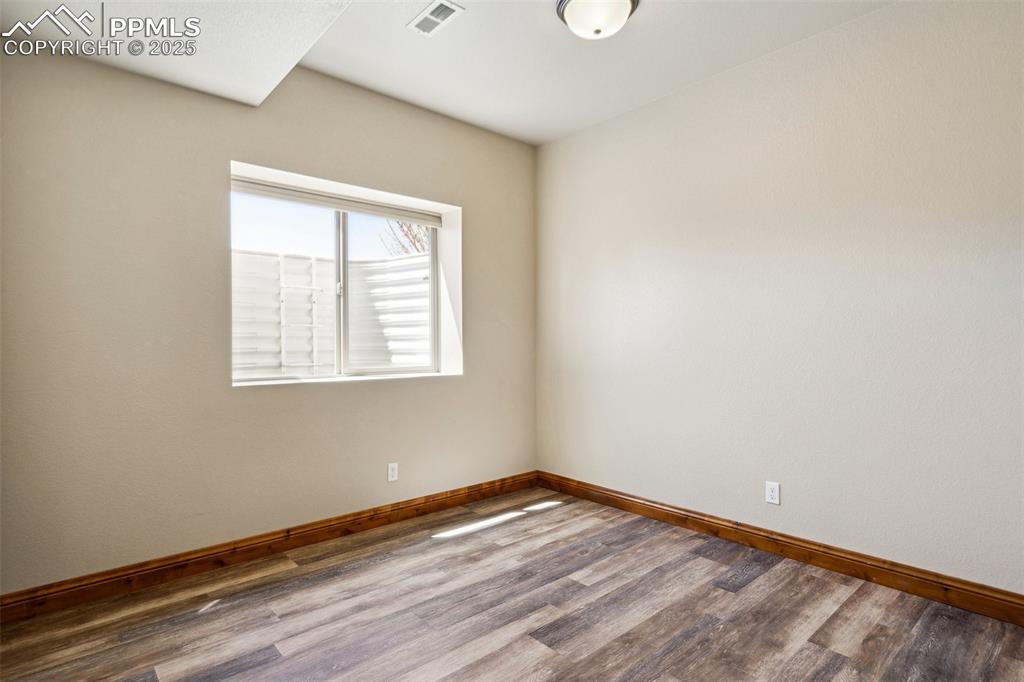 Image 28 of 46: Spare room featuring wood finished floors, baseboards, and visible vents