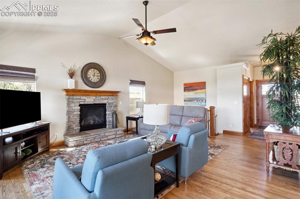 Image 3 of 46: Living area featuring baseboards, a stone fireplace, a ceiling fan, wood fi