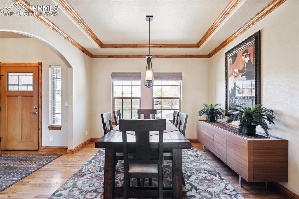 Image 7 of 46: Dining room featuring crown molding, a raised ceiling, arched walkways, and