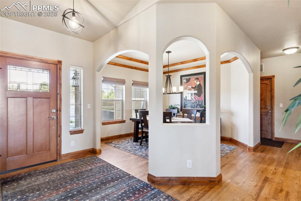 Image 8 of 46: Foyer featuring baseboards, arched walkways, a chandelier, light wood-style