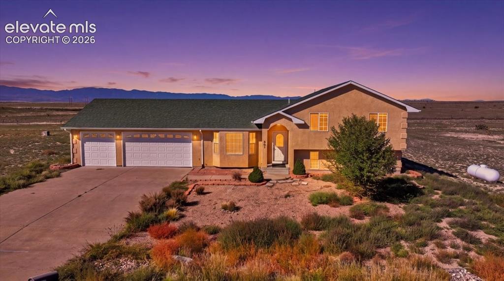 Caption: Stucco exterior with an arched entryway, multiple windows, and a three-car garage