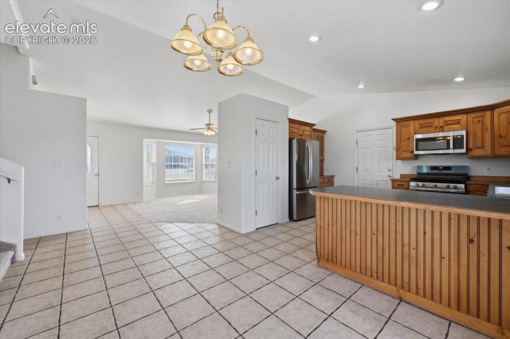 Image 12 of 46: Kitchen featuring wood cabinetry, stainless steel appliances, and a breakfa