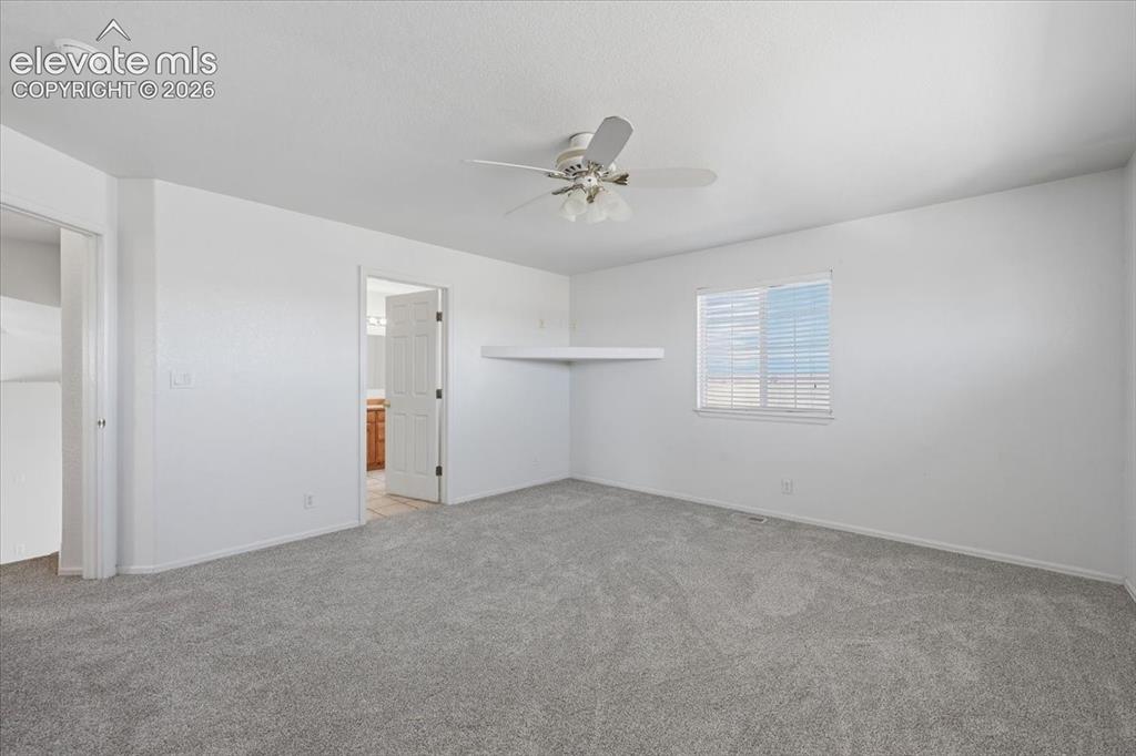 Image 15 of 46: Spacious room featuring light gray carpet flooring, a ceiling fan with inte