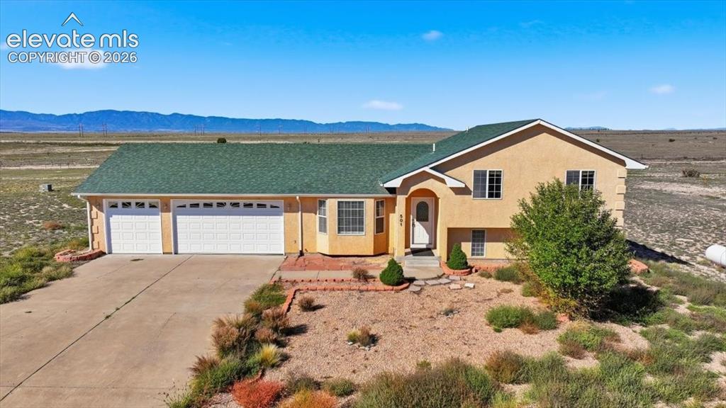Image 2 of 46: Stucco exterior with a green shingle roof, arched entryway, and a three-car